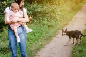 Dog looking at young mom holding her toddler