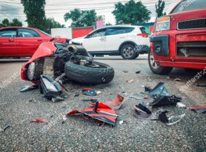 Crash scene with debris scattered on the road near multiple vehicles and a motorcycle