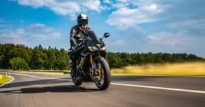 Motorcyclist wearing protective gear riding on a curved rural road