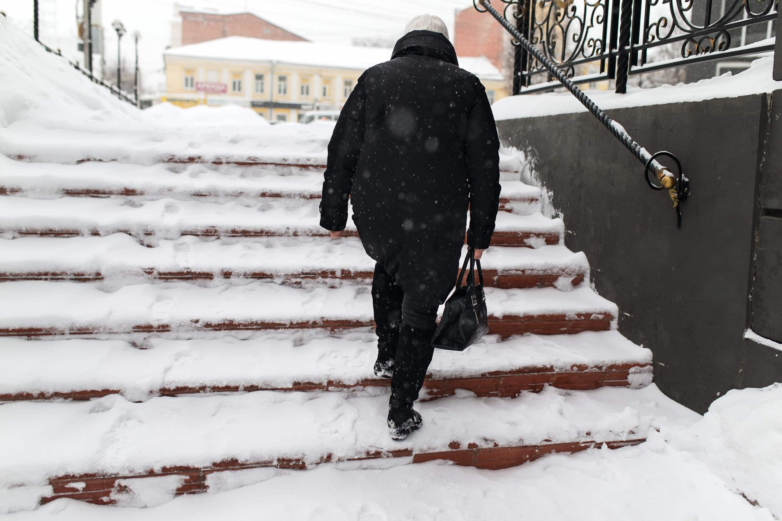 person walking up snowing steps that are a slip-and-fall hazard