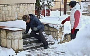 Older man slipping on icy steps in the winter with wife besides him