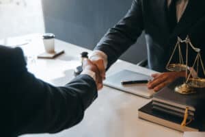 lawyer shaking hands with clients after discussing wrongful death and surivival actions
